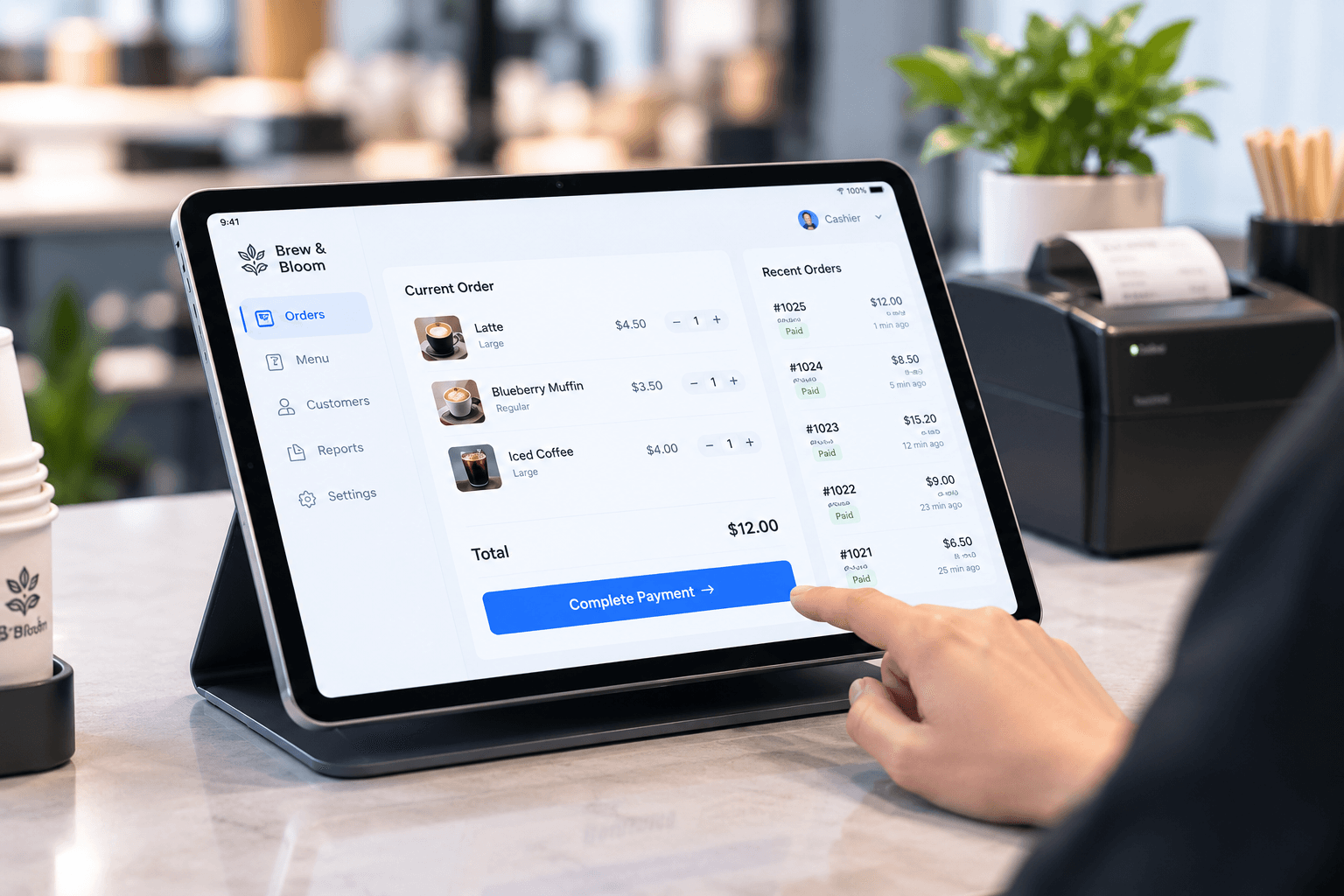 A hand completing payment on a tablet till beside a receipt printer.